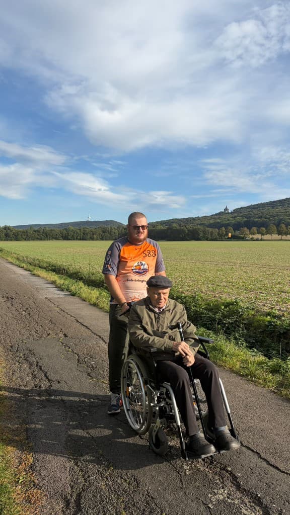 Andreas Böse accompanying a client in a wheelchair outdoors